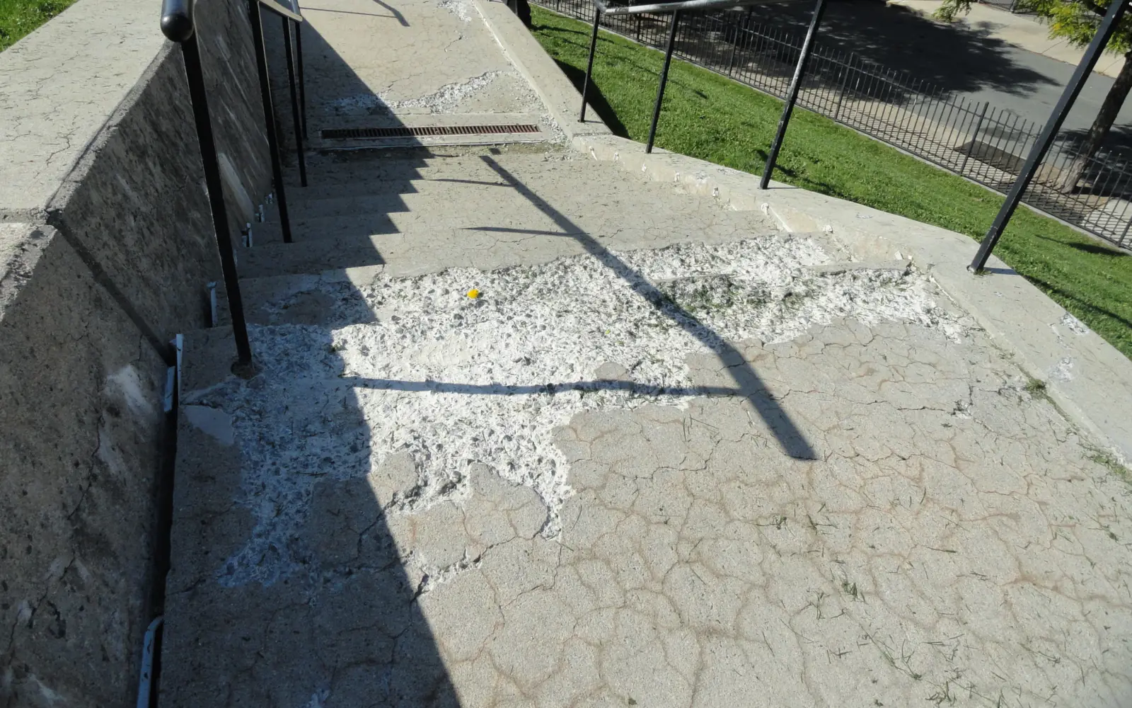 Weathered concrete landing with cracked, spalled and patched areas