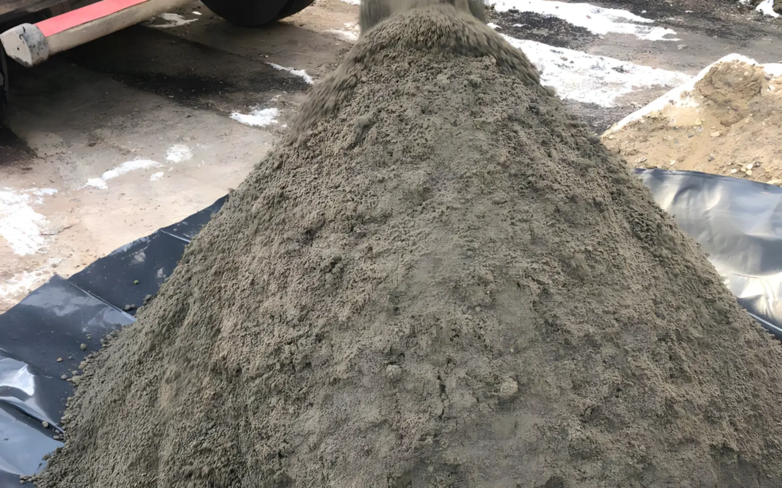 Heap of sand and cement screed mix tipped onto polythene sheeting
