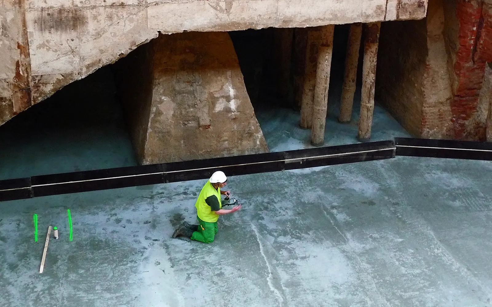 Worker on a freshly placed concrete base in a deep excavation